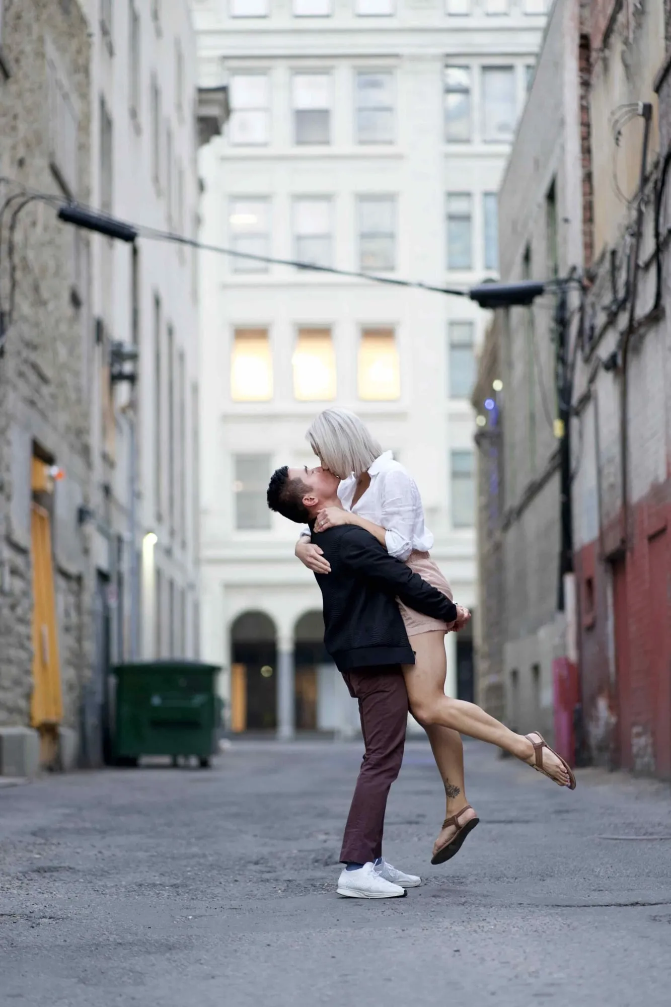 Man lifting his fiancée off her feet in a downtown alley