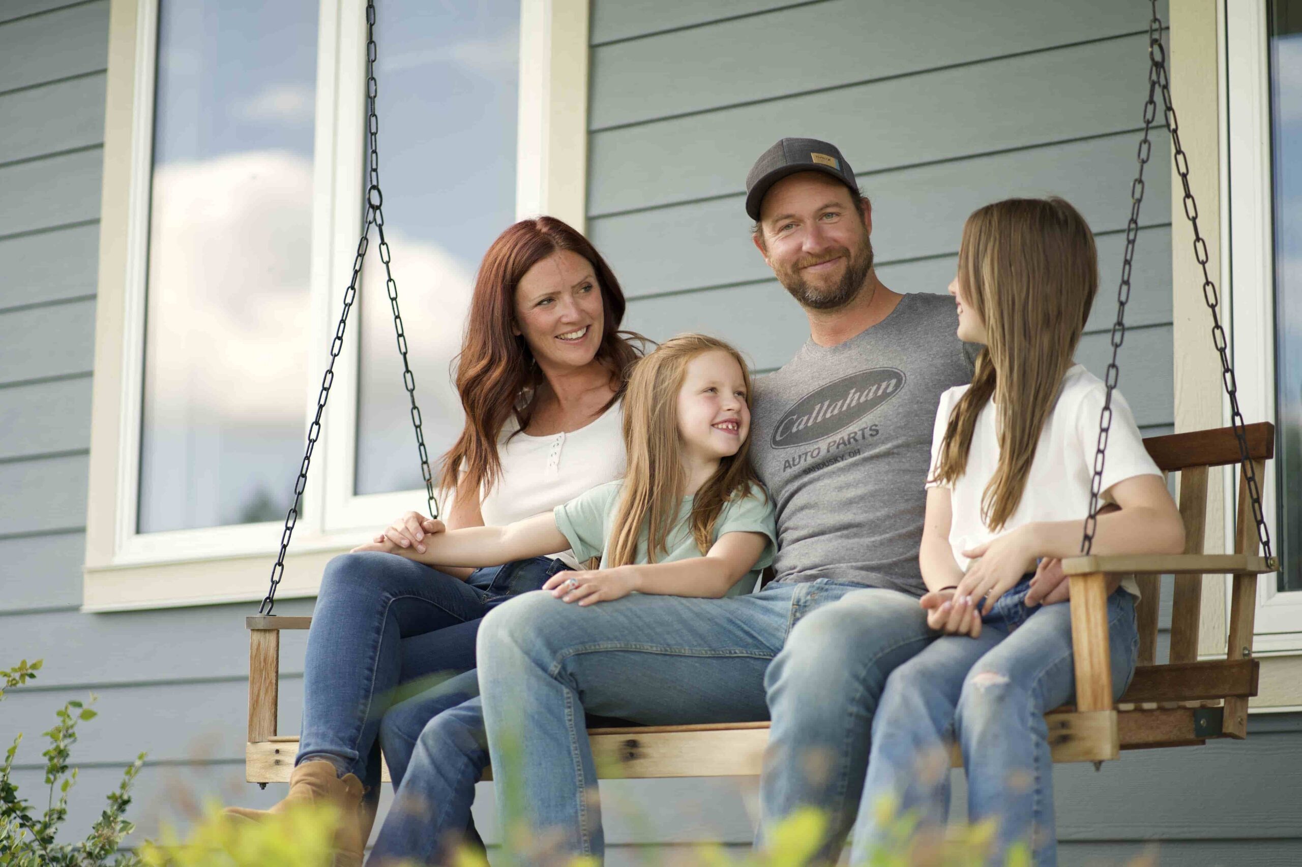 Family of four smiling together on a porch swing